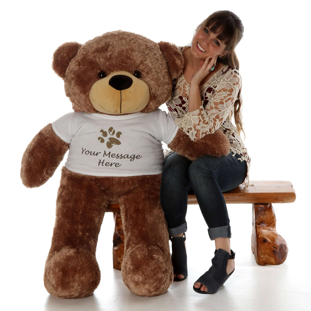 A young woman sits on the bench with a brown teddy bear.